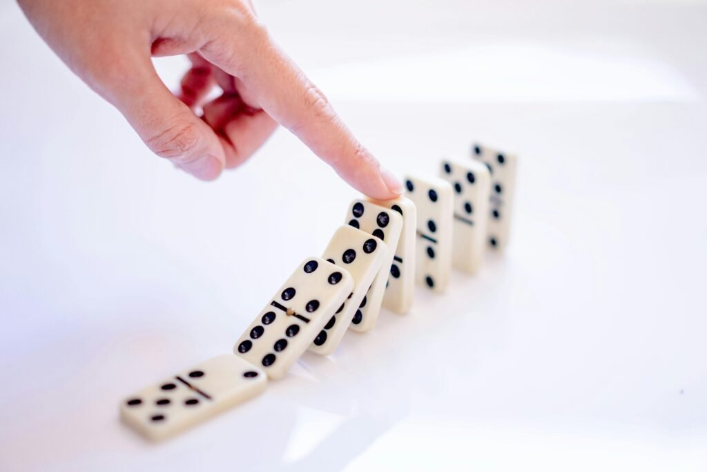 A close-up shot of a hand pushing dominoes, illustrating cause and effect.